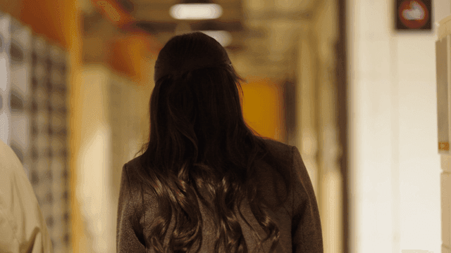 Back view of woman walking down hallway