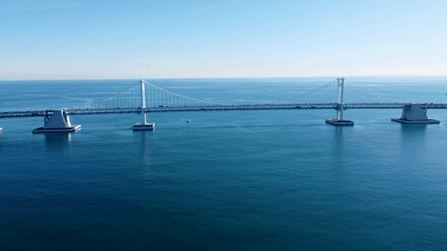 Long bridge over calm blue sea.