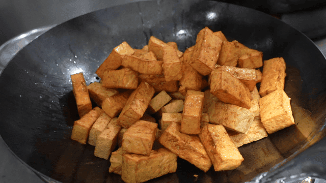 Fried tofu cubes poured into wok