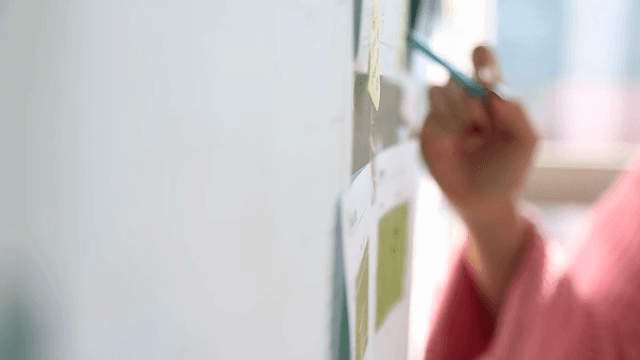 펜으로 보드를 가리키며 회의하는 손