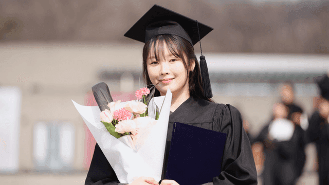 Graduate holding flowers and diploma