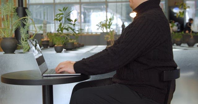 Man Working on Laptop in Office with Plant Landscaping