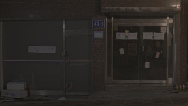 골목에 있는 건물의 현관문을 열고 들어가는 두 여학생