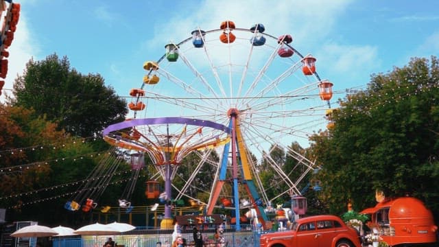 Daytime amusement park with Ferris wheel and swinging chairs