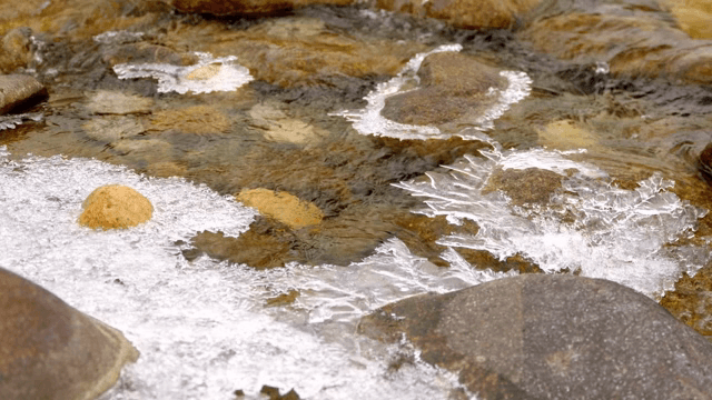 Small stream flowing through icy rocks