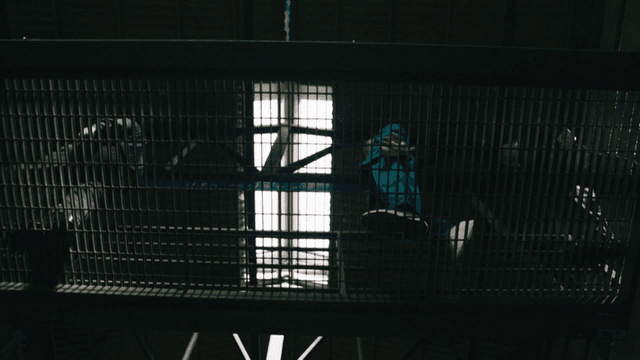 Prisoners and guards moving across metal lattice bridge