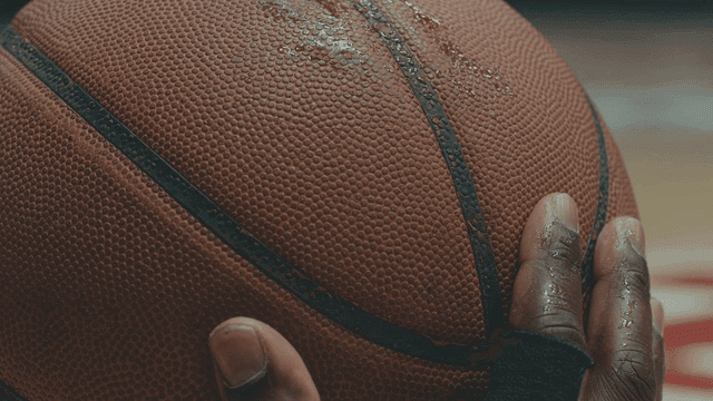 Black hand holding wet basketball