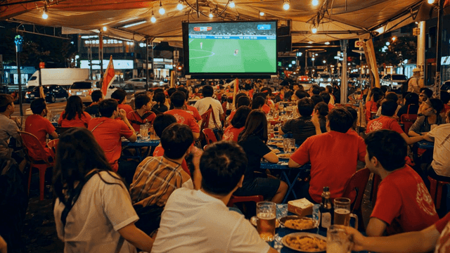 People at food stall watching soccer match