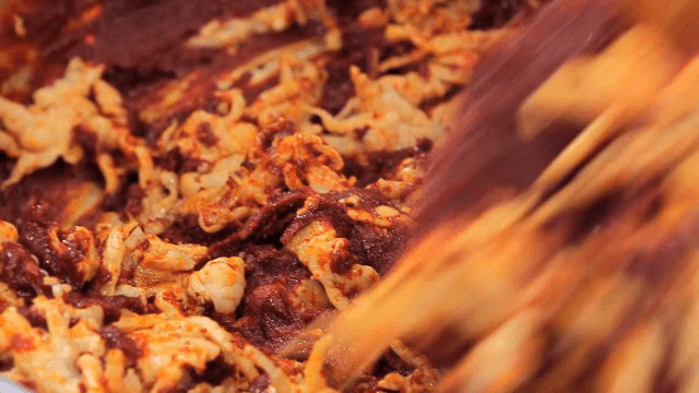 양념된 닭발을 용기에 섞는 장면