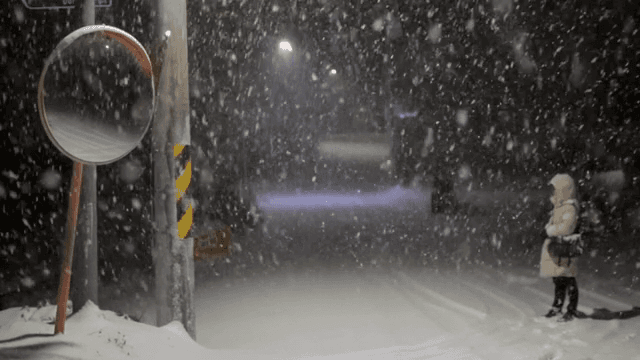 눈 내리는 밤 거리에서 걷는 사람