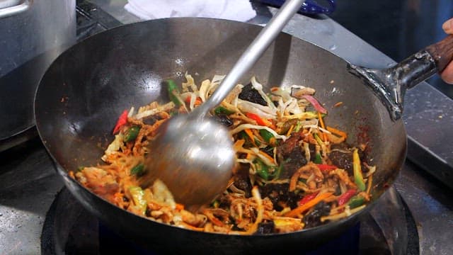 웍에서 매운 소스로 야채와 고기를 볶는 장면