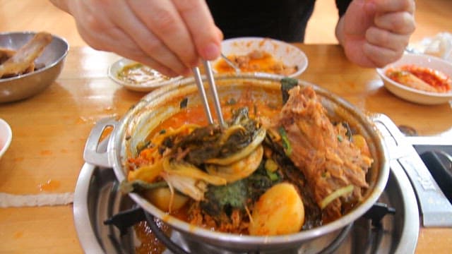 Hands that takes the meat out of the napa cabbage and pork backbone stew