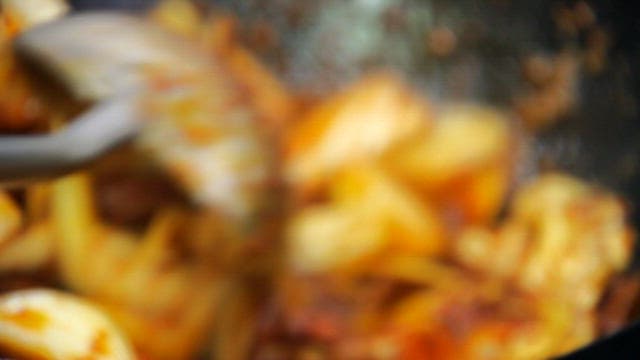 Spicy stir-fried octopus being cooked on wok in kitchen