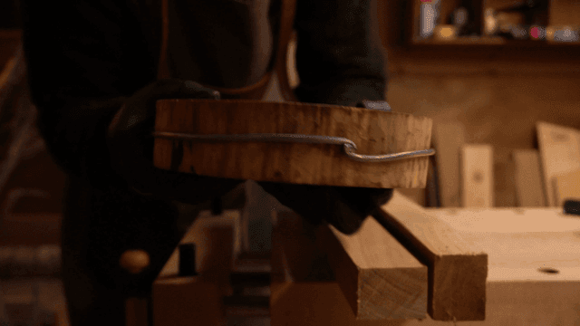 작업장에서 와이어를 감은 나무 조각을 살펴보는 장인