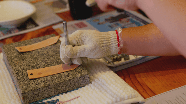 정교하게 가죽 태그에 망치로 각인하는 손