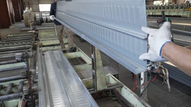 Workers handling metal sheets in a factory