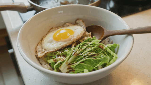 Bowl containing fried eggs and fresh vegetables