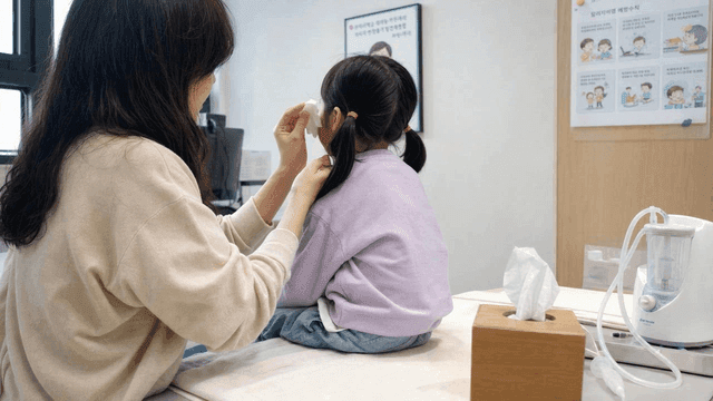 Mother wiping away her child's tears in doctor's office