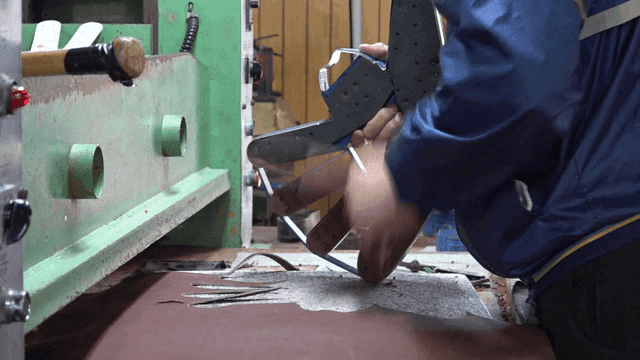 Worker cutting leather to fit glove mold