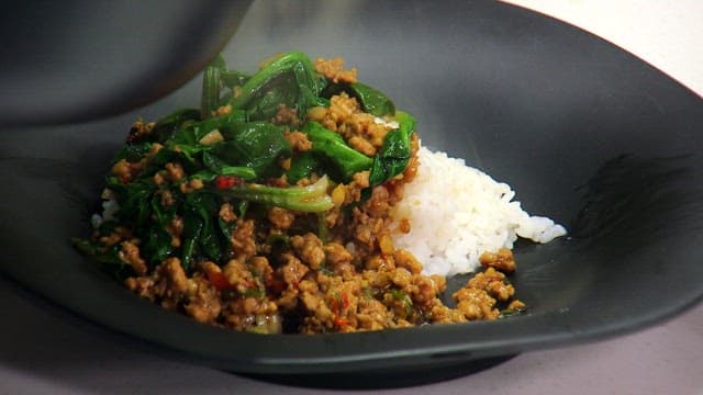 Bowl of rice topped with well-stir-fried meat and spinach