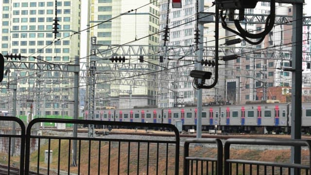 Subway train running on tracks in an urban area with buildings visible