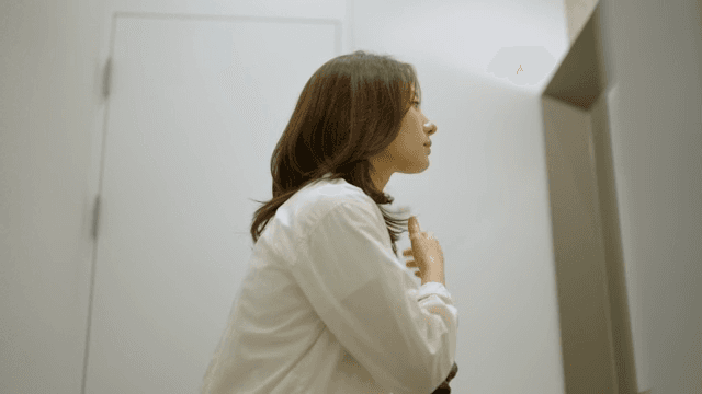 화장실에서 거울을 보며 머리를 정리하는 여성