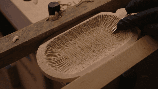 정교한 패턴의 나무 조각을 작업하는 손