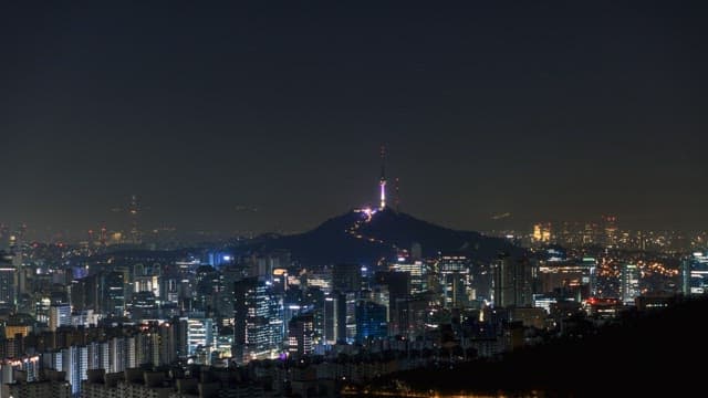 Cityscape at night with illuminated tower and crescent moon