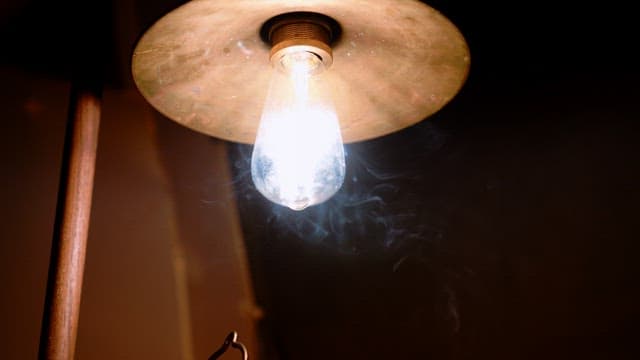 Lightbulb of a lamp illuminating the rising smoke