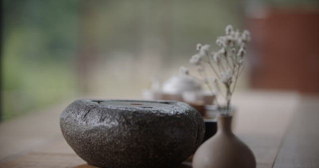 물이 든 유리 찻주전자를 돌 표면에 내려놓는 손