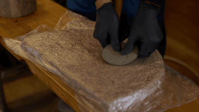 나무와 톱밥을 돌로 눌러 고정하는 목공예가