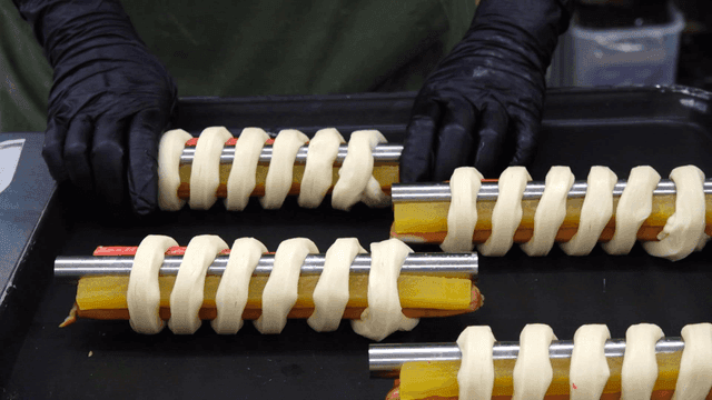 빵 반죽으로 감싼 꼬치를 오븐 트레이에 준비하는 모습