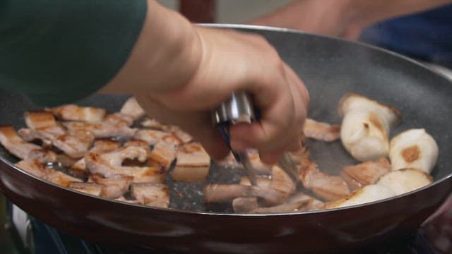 Frying pork belly and chili peppers on a frying pan