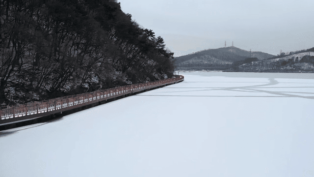 나무 산책로가 있는 눈 덮인 호수
