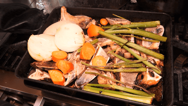 Scene of grilling vegetables and beef bones in kitchen