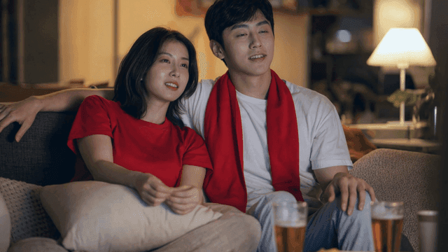 Couple cheering for soccer on sofa at home
