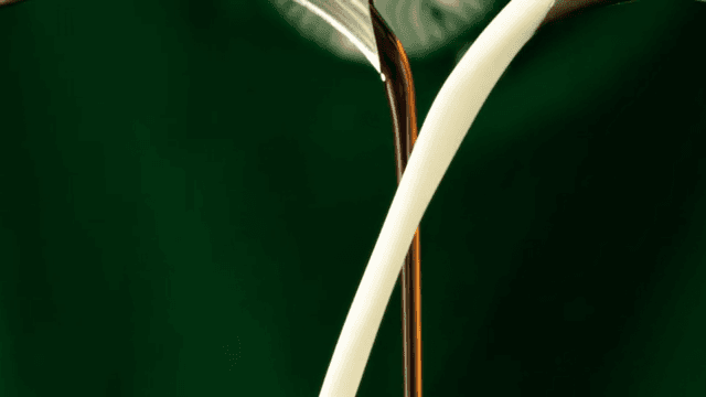 White milk and brown coffee poured against a green screen
