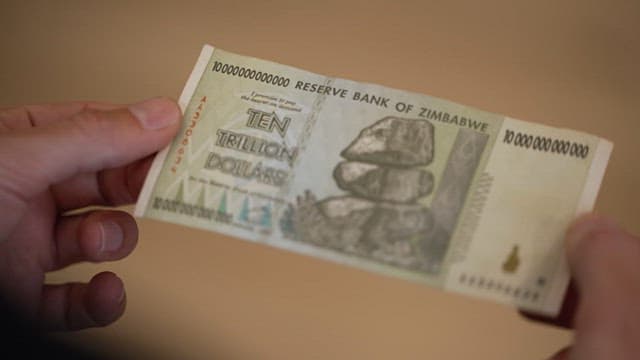 10조 짐바브웨 달러 지폐를 들고 있는 손