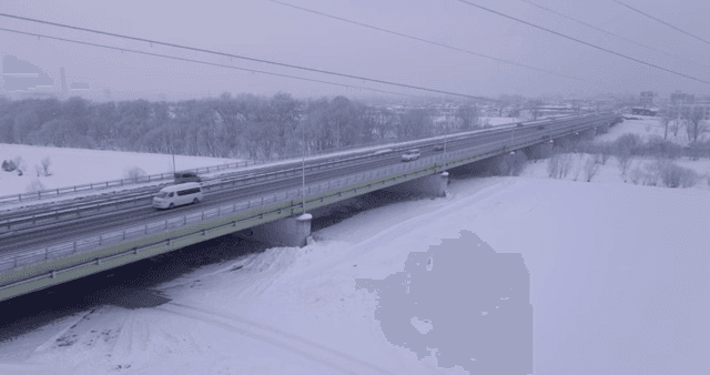 Snow-covered bridge with moving vehicles