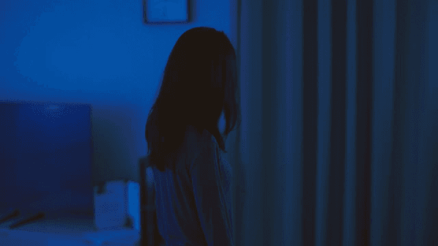 어두운 방에 서 있는 얼굴에 상처가 난 여성