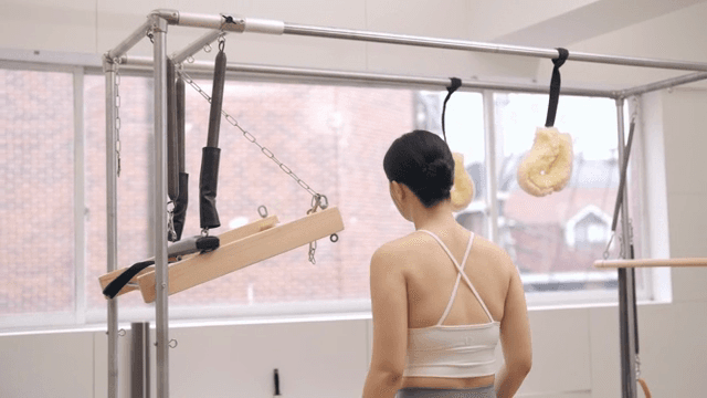 실내에서 필라테스 기구를 조정하는 여성