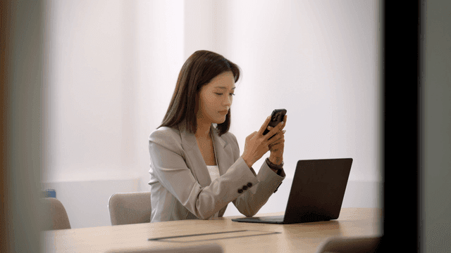 Female office worker looking at her laptop and phone in front of her
