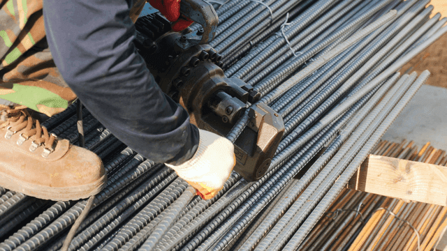 Worker cutting steel bars at a construction site