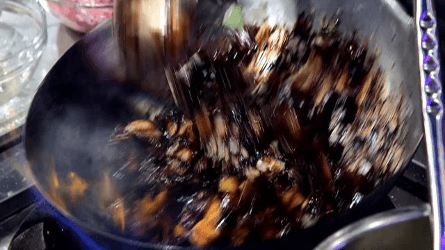 뜨거운 웍에서 짜장 소스와 감자를 섞는 모습