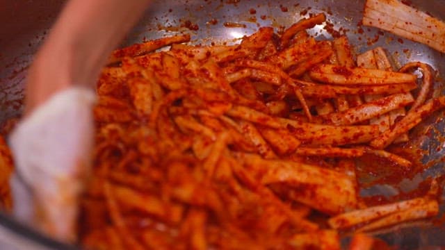 큰 그릇에서 고춧가루를 섞어 무생채 만들기