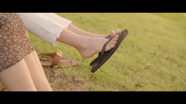 Feet of women resting on grass wearing sandals