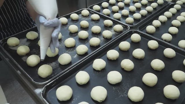 Pastry chef applying cream to dough in the kitchen