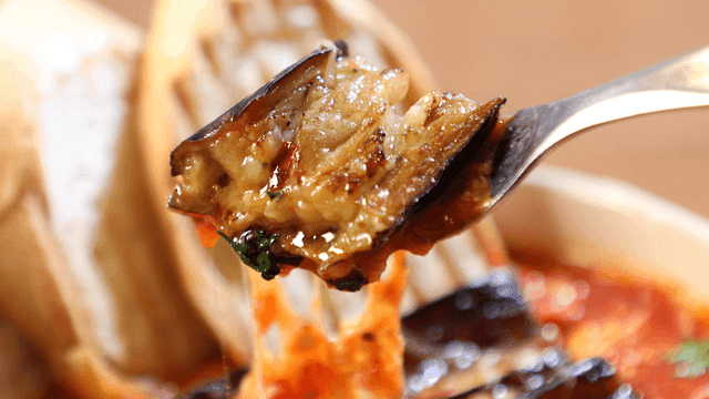 Fork serving eggplant gambas with tomato sauce and bread