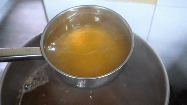Ladle scooping broth from a boiling pot