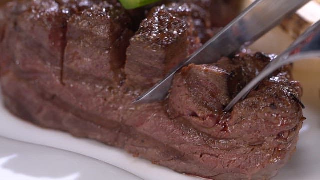 Juicy beef steak being sliced with a knife